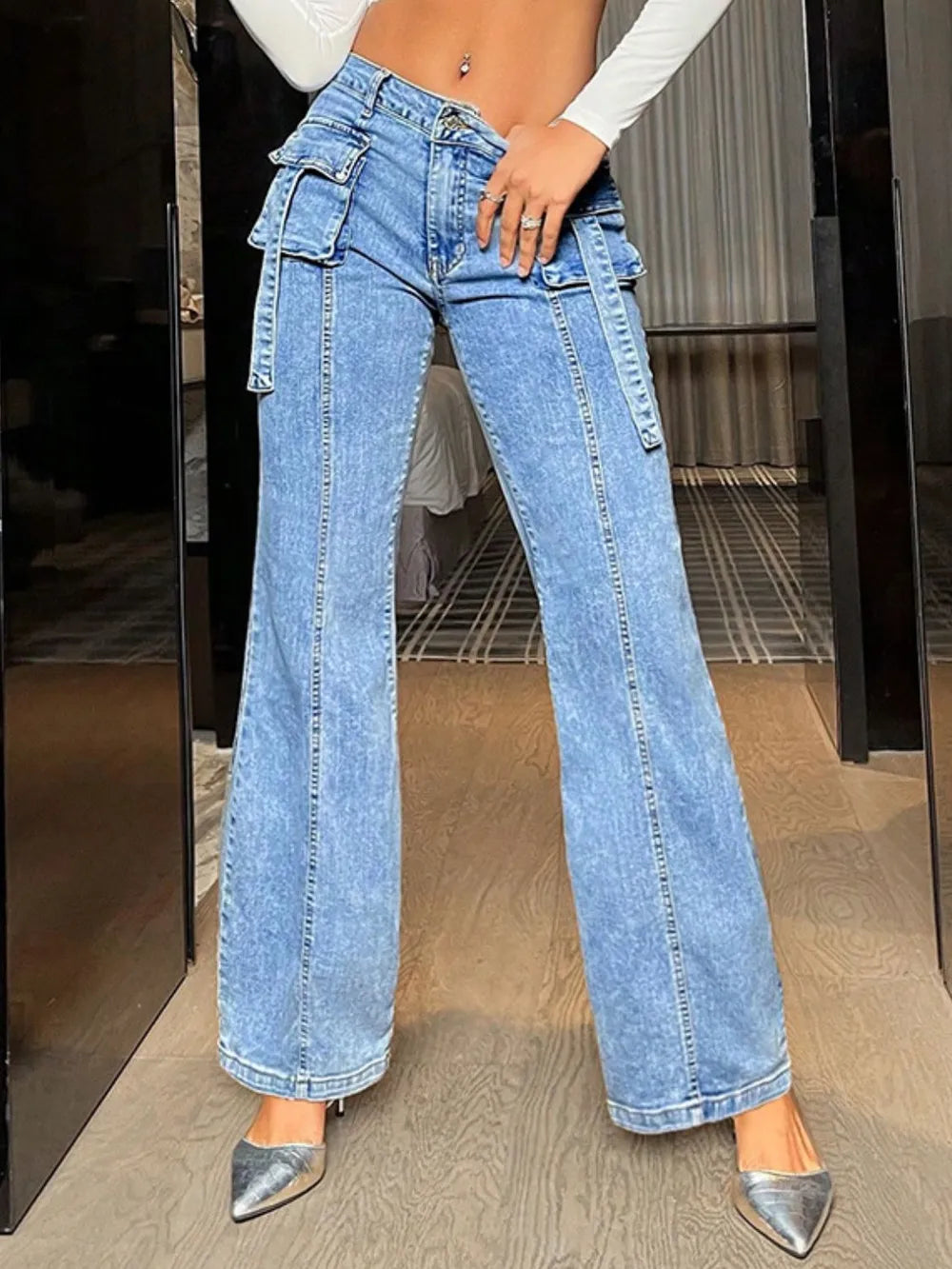 Person wearing high-waisted blue jeans with a blurred indoor background