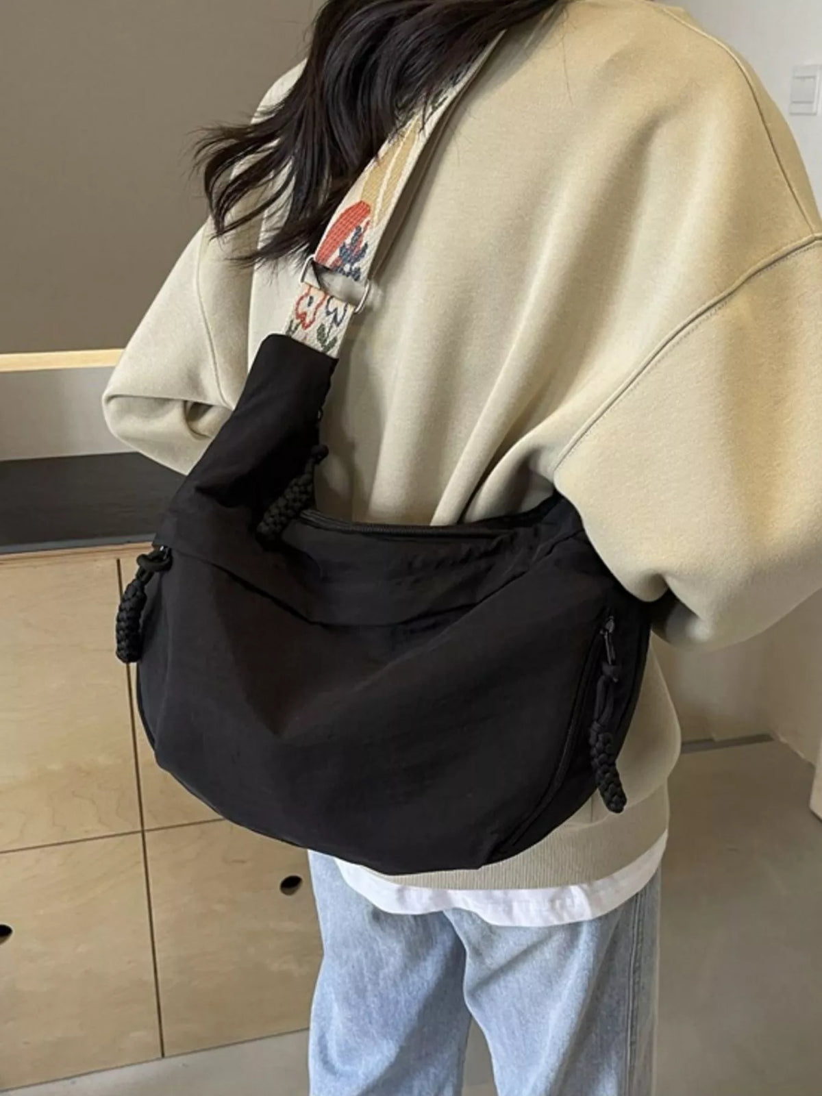 Person wearing a black waist bag with a colorful strap in an indoor setting