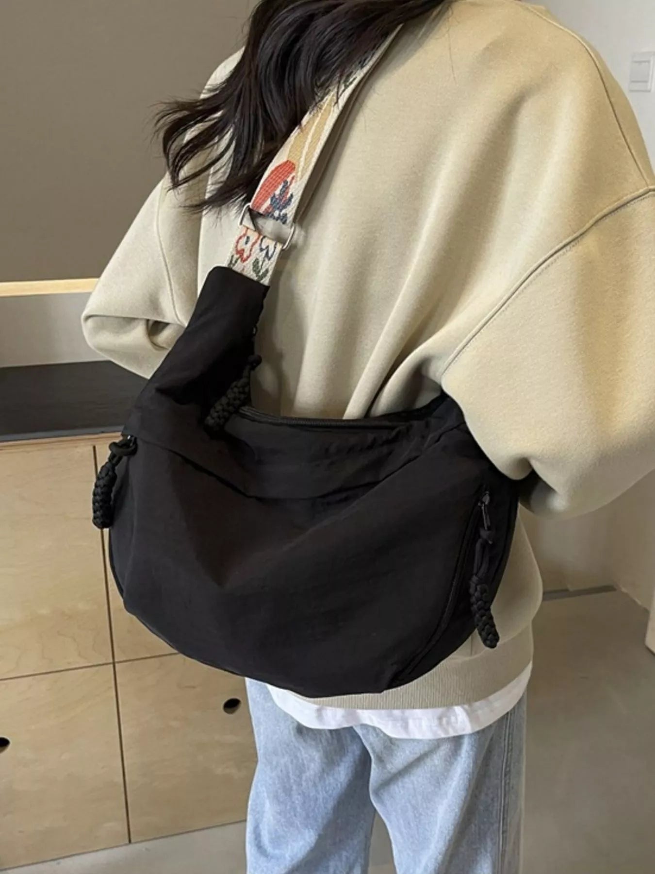Person wearing a black waist bag with a colorful strap in an indoor setting