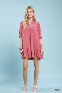 Woman wearing a pink dress with lace details on a light blue background