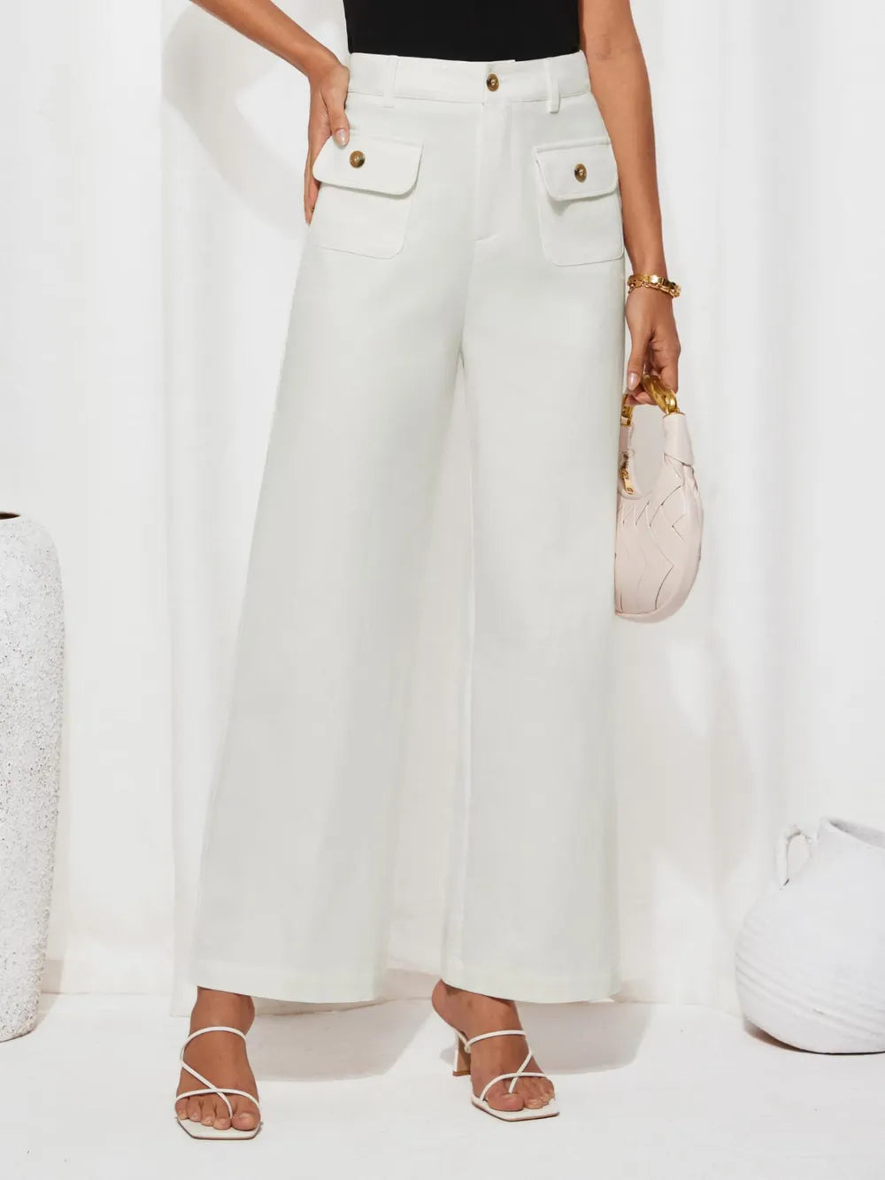 Person wearing white wide-leg pants with gold buttons on a white background