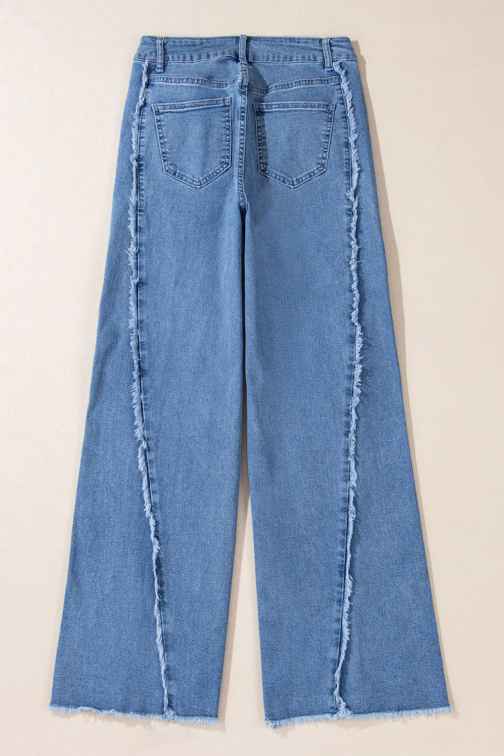 Blue jeans with frayed edges on a beige background