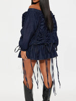 Navy off-shoulder dress with ruched details and long boots on a white background