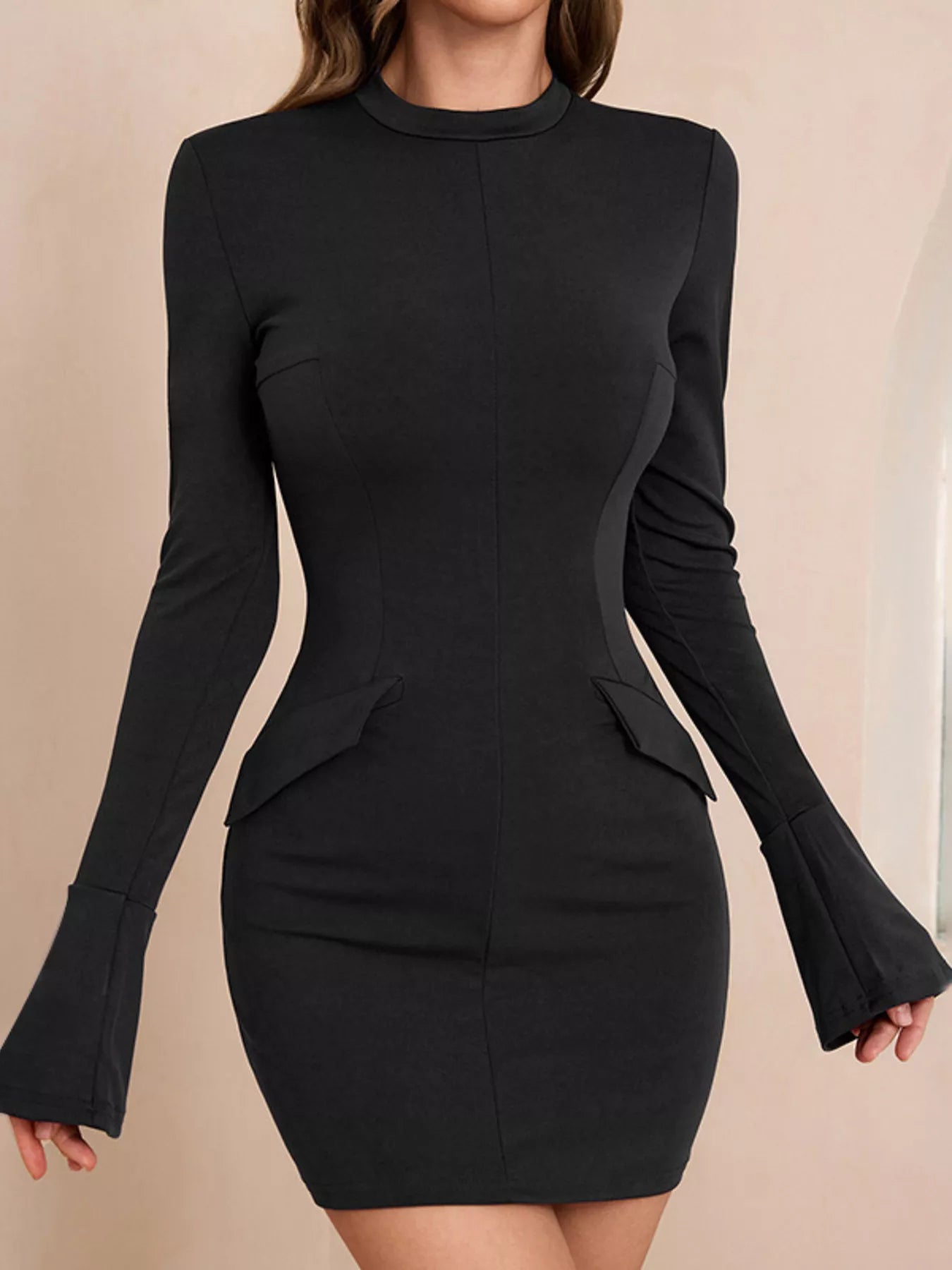 Black long-sleeve dress with flared cuffs on a beige background
