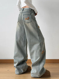 Light blue jeans with patches worn by a person on a plain background