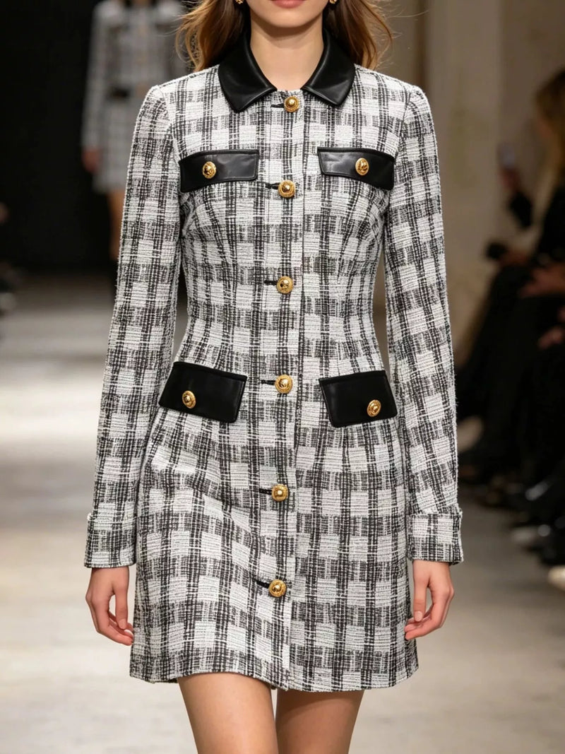 A model on a runway wearing a black and white plaid tweed mini dress with black leather-look collar, pocket flaps, and gold-tone buttons.