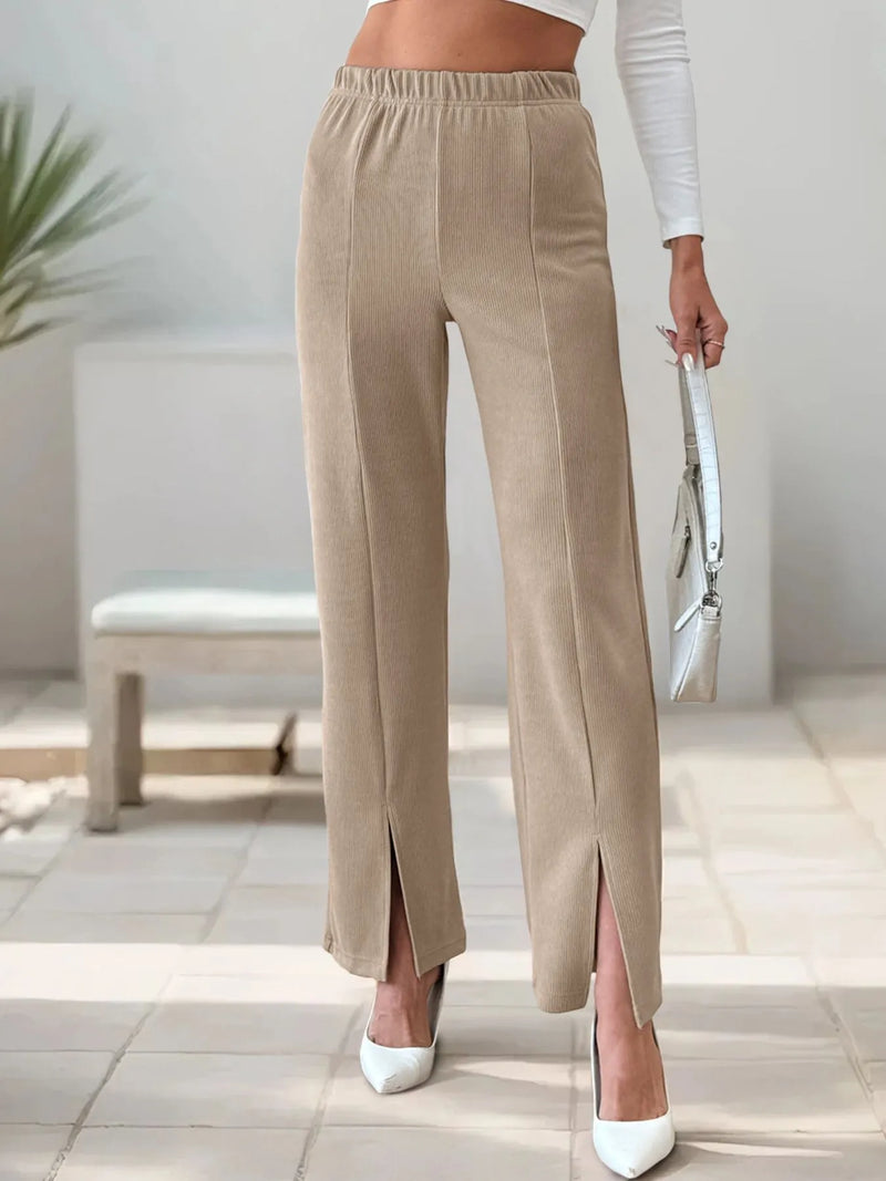 Beige wide-leg pants worn by a person in a minimal indoor setting.