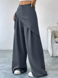 Person wearing gray wide-leg pants in a minimal indoor setting