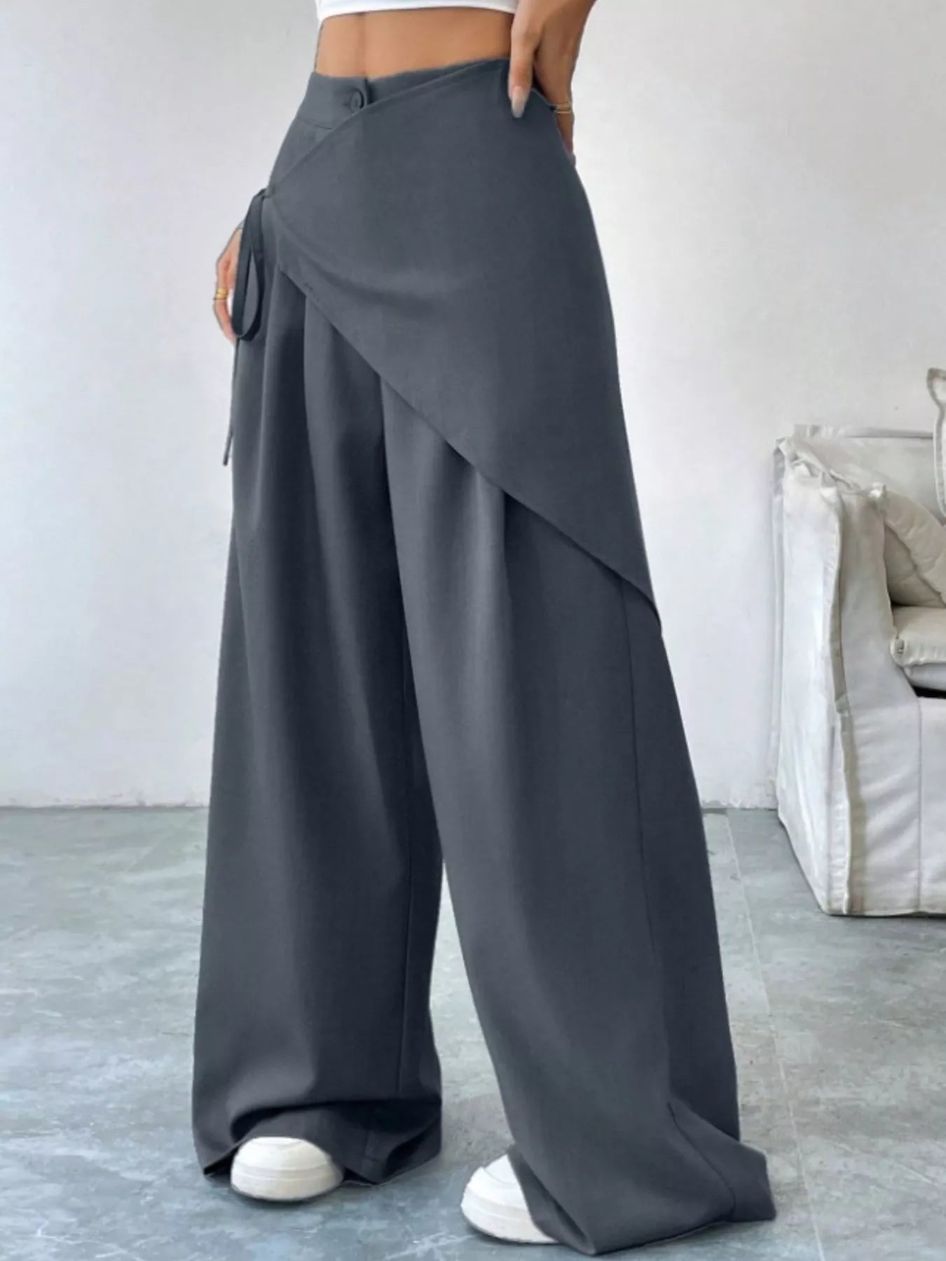 Person wearing gray wide-leg pants in a minimal indoor setting