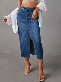 Person wearing a long blue denim skirt with a plain background
