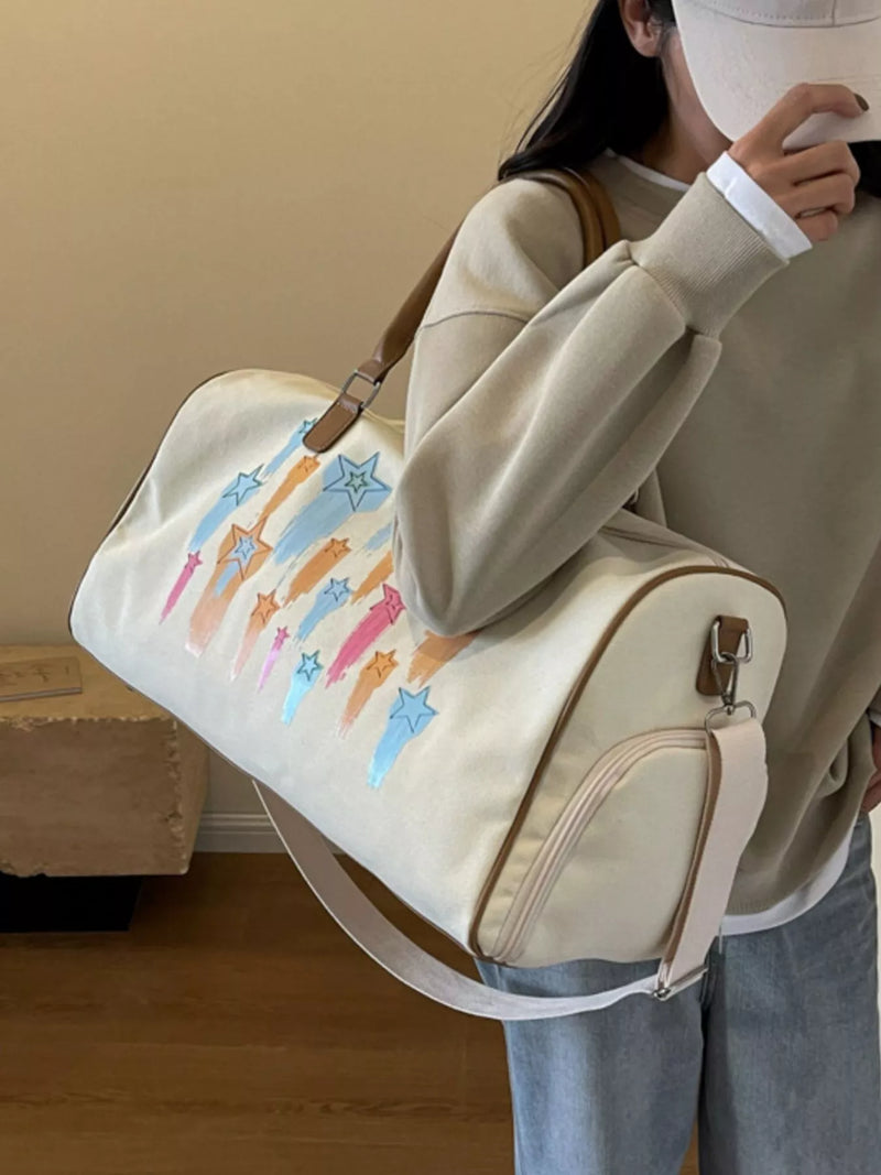 Person holding a beige duffel bag with colorful cat illustrations.