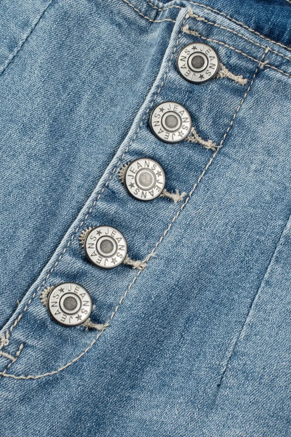 Close-up of blue denim fabric with metal buttons