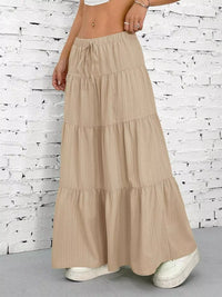 Beige tiered skirt worn by a person against a white brick wall.