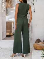 Woman wearing a green jumpsuit standing in a modern indoor setting.