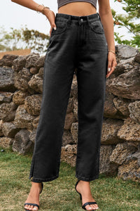 Person wearing black high-waisted jeans standing in front of a stone wall.