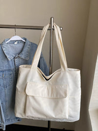 White tote bag hanging on a rack with a denim jacket in the background