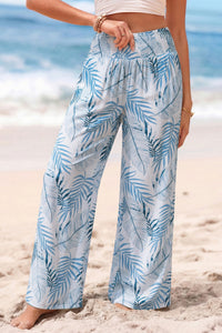 Person wearing blue and white leaf-patterned pants on a beach.