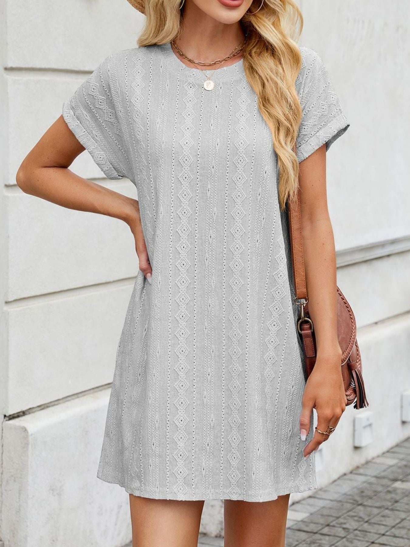 Woman wearing a gray patterned dress against a light background