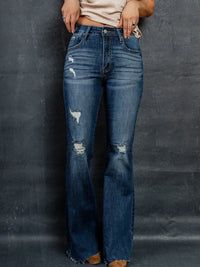 Person wearing blue flared jeans against a dark background