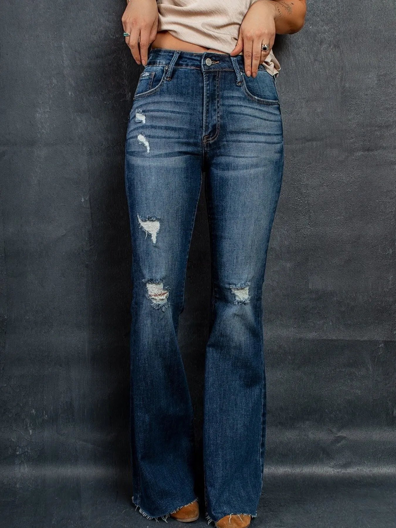 Person wearing blue flared jeans against a dark background