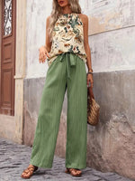 Woman wearing a floral top and green pants standing on a street.