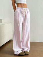 Person wearing pink striped pajama pants in a minimalistic room.