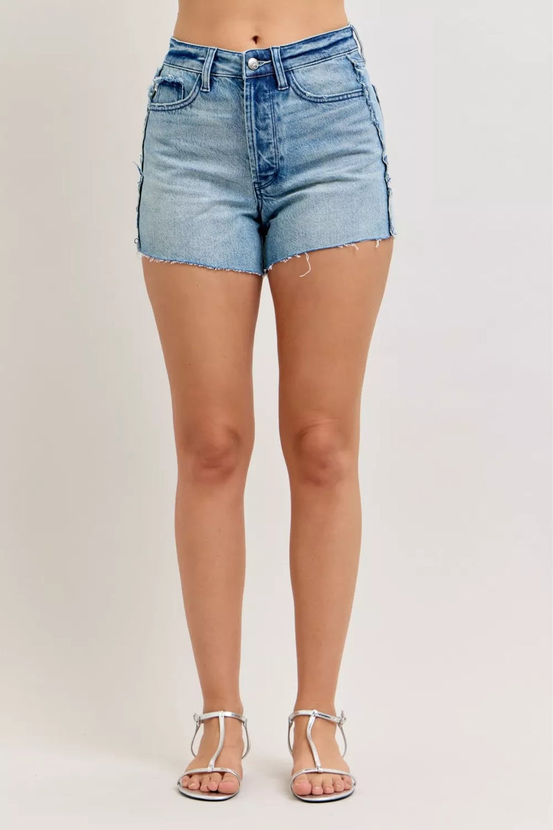 Denim shorts worn by a person on a plain background