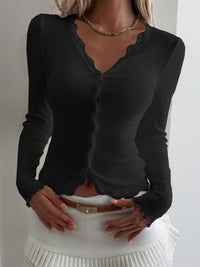 Black long-sleeve top worn by a person against a white background