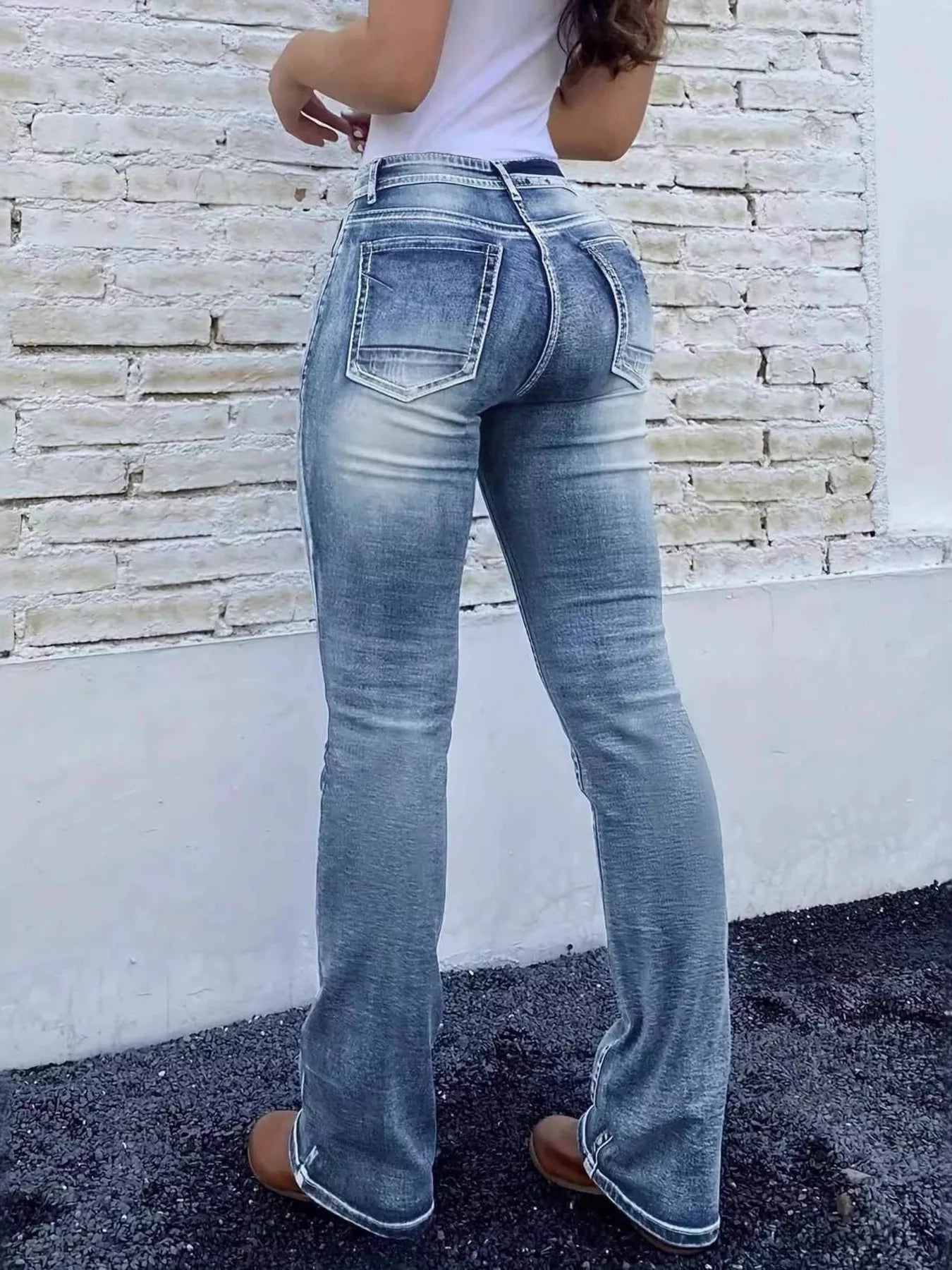 Person wearing blue jeans with a stone wall background