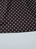 Close-up of a brown fabric with white polka dots on a light gray background