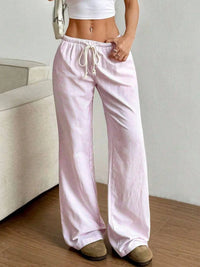 Person wearing light pink pajama pants with a white top in a minimal indoor setting.