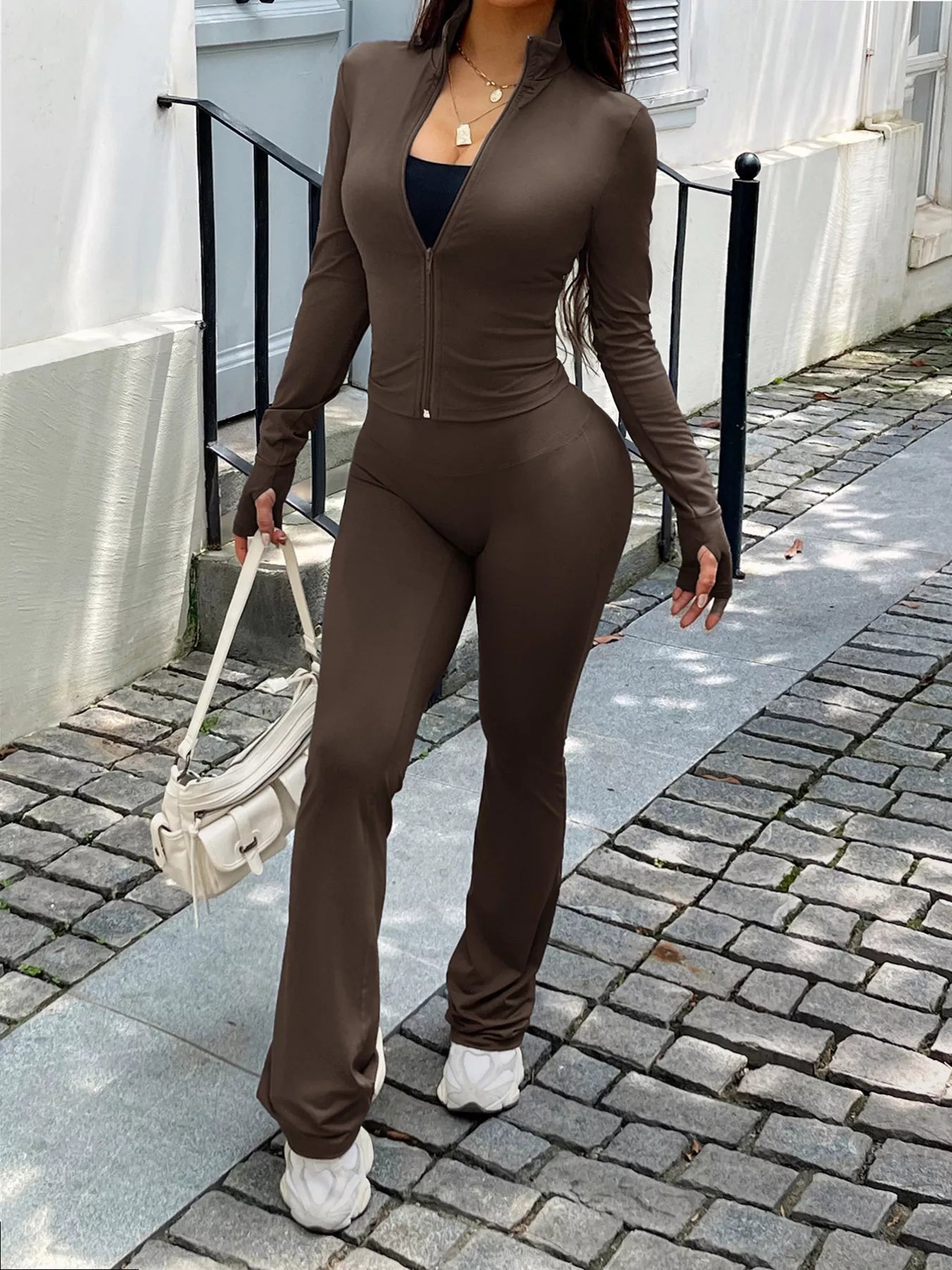 Person wearing a brown outfit walking on a sidewalk.