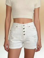 Person wearing a beige ribbed crop top and light denim shorts on a beige background