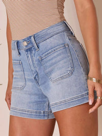 Person wearing light blue denim shorts on a beige background