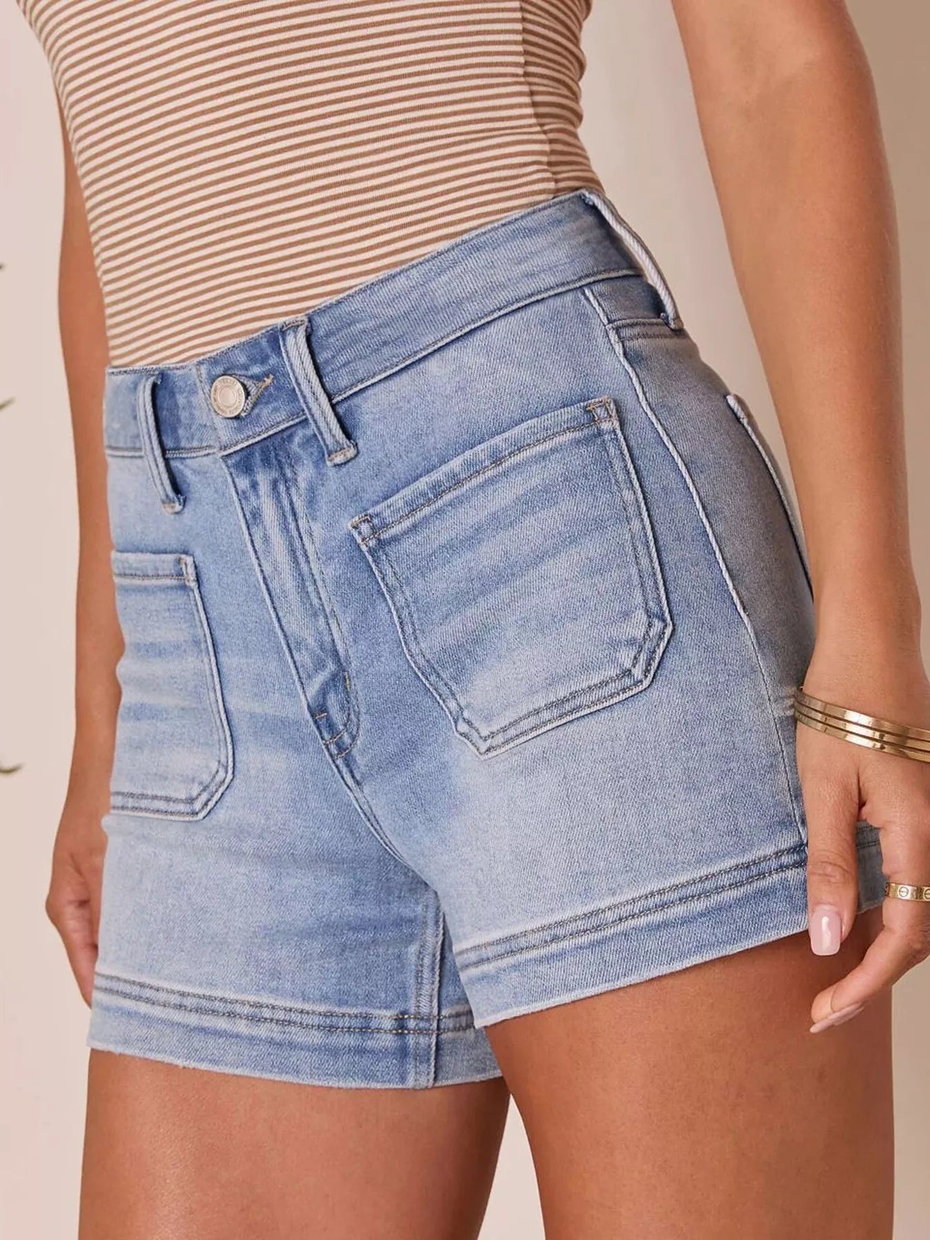 Person wearing light blue denim shorts on a beige background
