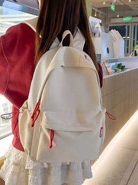 Person wearing a white backpack with red drawstrings in an indoor setting