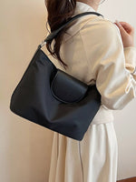 Person wearing a black handbag with a neutral background