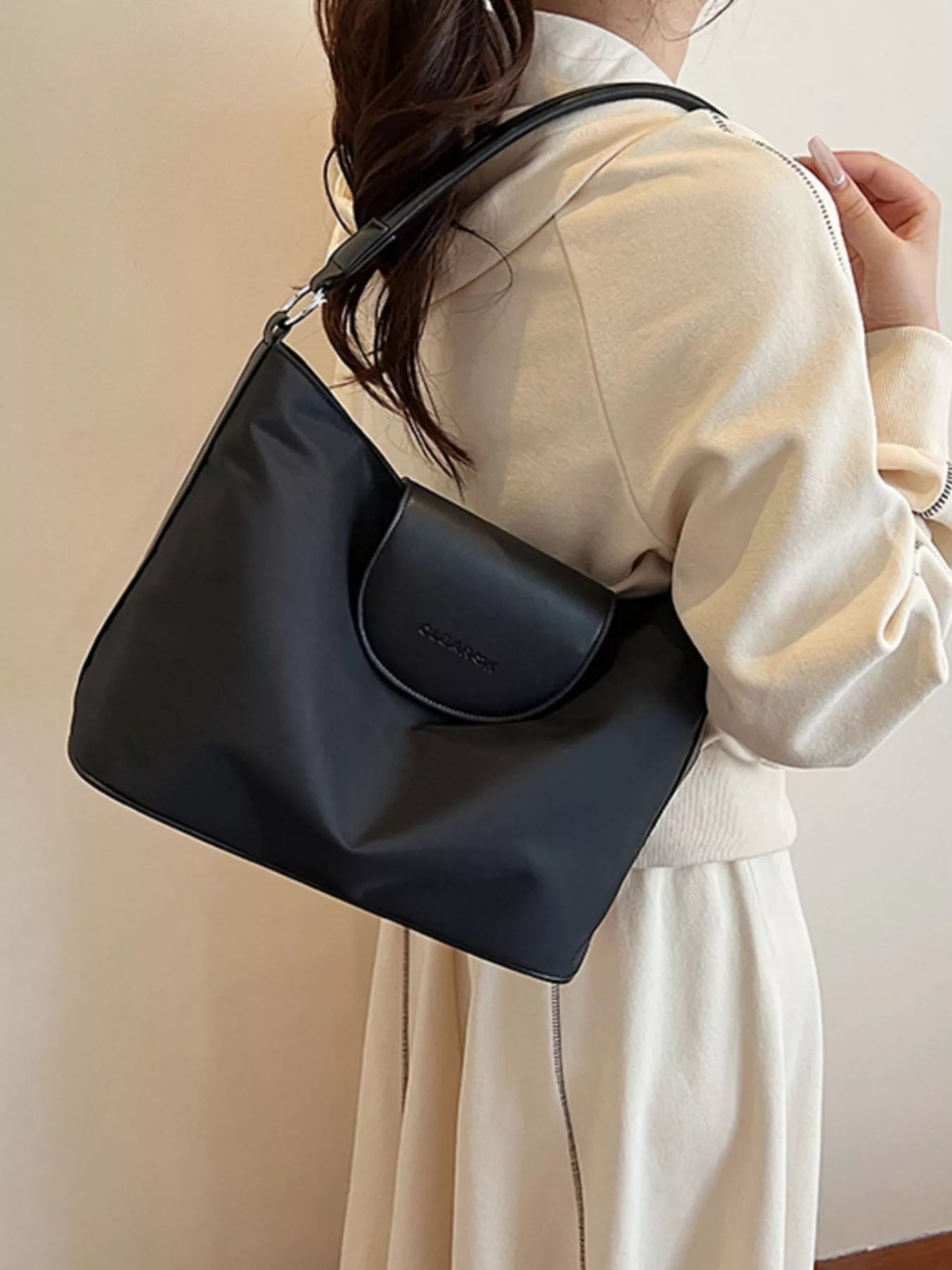 Person wearing a black handbag with a neutral background