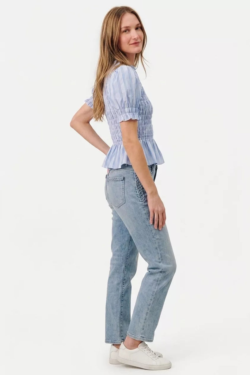 Woman wearing a light blue top and jeans on a white background