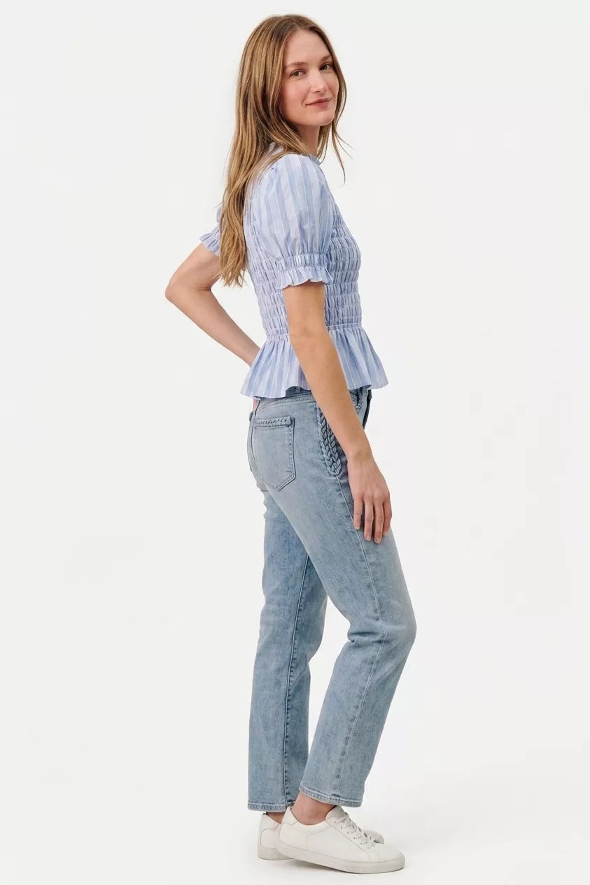 Woman wearing a light blue top and jeans on a white background