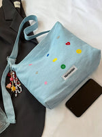 Light blue handbag with colorful polka dots and a visible brand label on a white surface.