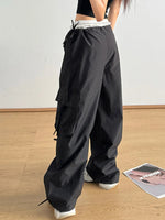 Person wearing black wide-leg pants with a white lace trim on a wooden floor.