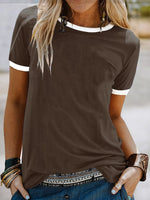 Woman wearing a brown t-shirt with white trim in an outdoor setting