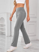 Person wearing gray flared pants and white sneakers in a minimalistic setting