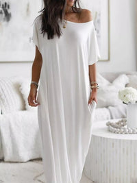 Woman wearing a white off-shoulder dress in a minimalistic room.