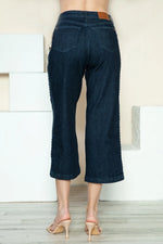 Dark blue jeans worn by a person standing against a neutral background
