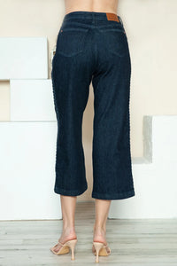 Dark blue jeans worn by a person standing against a neutral background