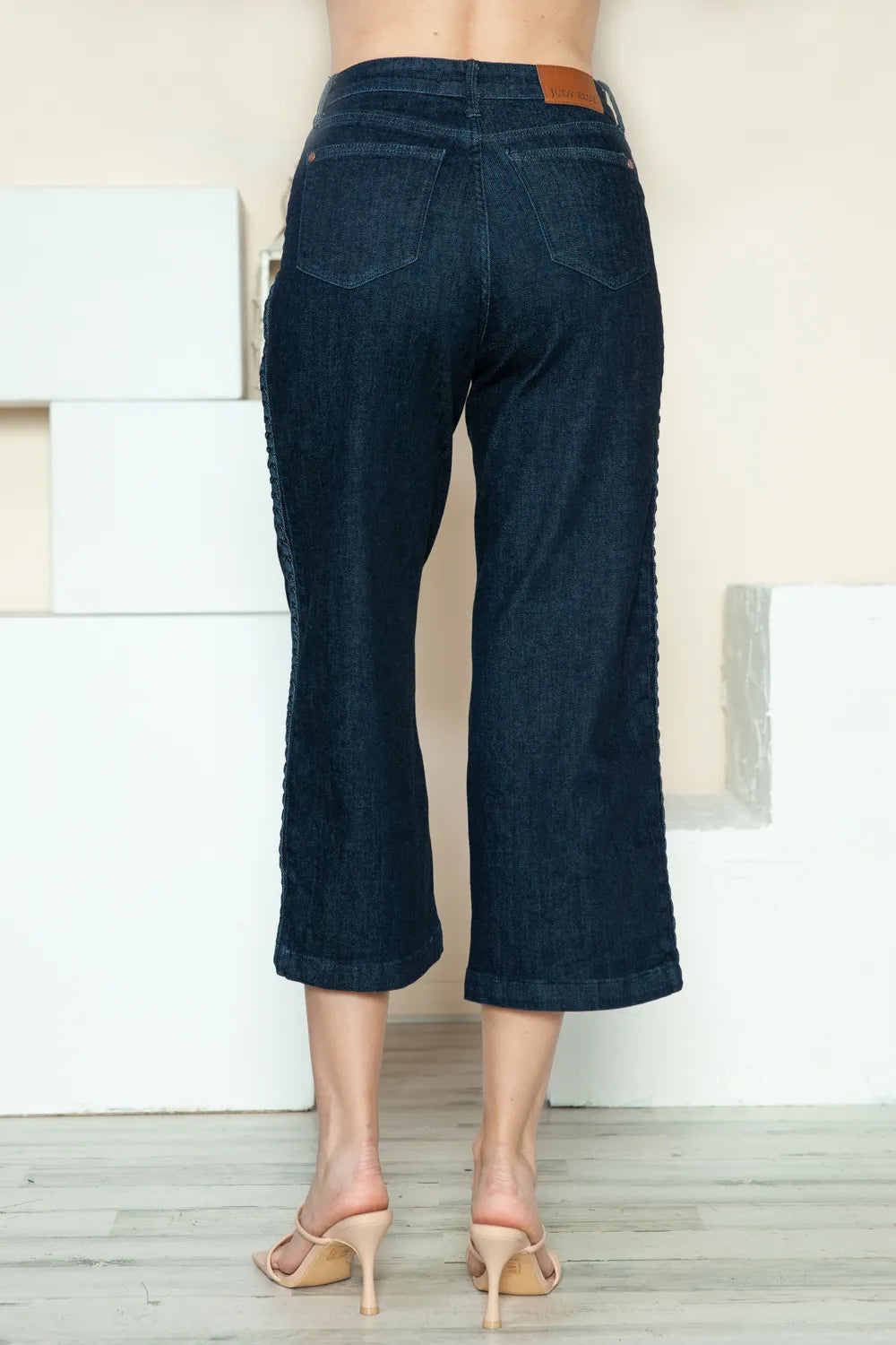 Dark blue jeans worn by a person standing against a neutral background