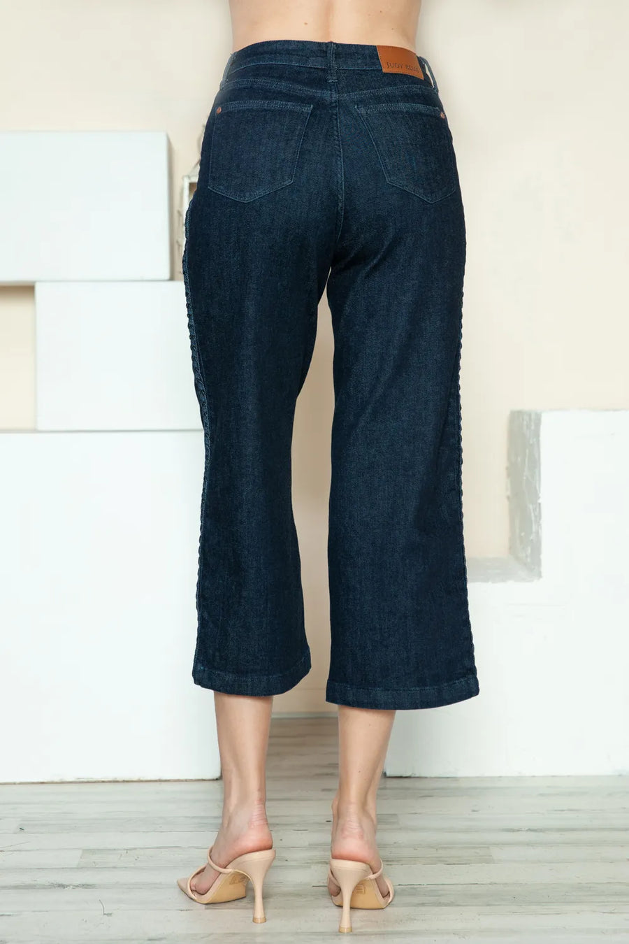 Dark blue jeans worn by a person standing against a neutral background