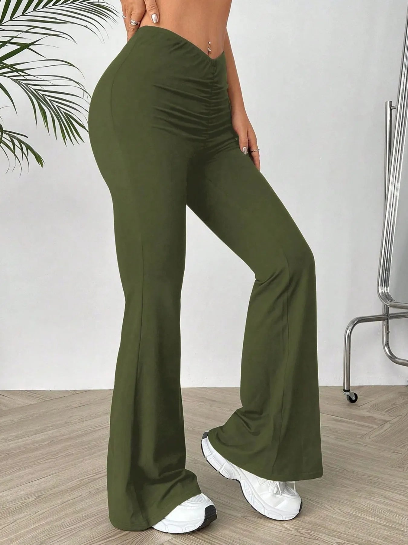 Green wide-leg pants worn by a person on a wooden floor with a white wall background
